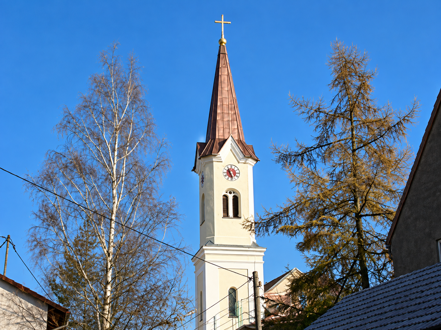 Kirchturm mit Kupferspitze und Herbstbäumen